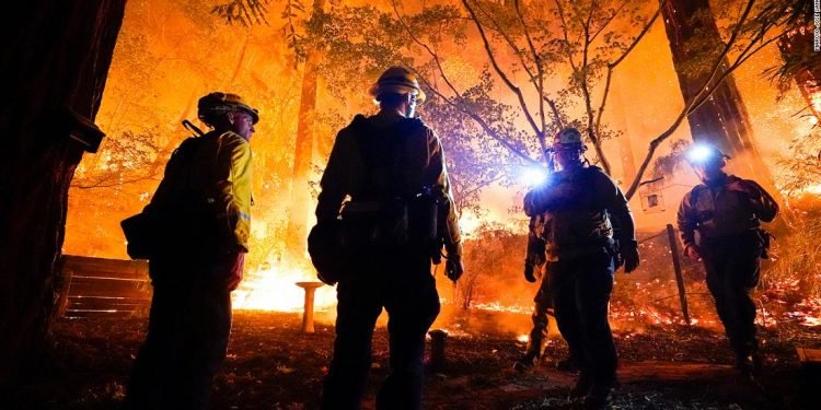 Firefighters make a stand in the backyard of a home in front of the advancing CZU August Lightning Complex Fire Friday, Aug. 21, 2020