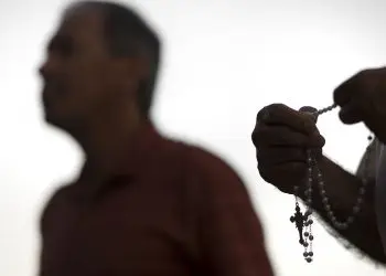 An attendee prays the rosary Oct. 1 during a public session on the issue of clergy sexual abuse at Our Mother of Confidence Parish Hall in San Diego. An abuse survivor in the Diocese of Syracuse, N.Y., is donating a large portion of a $5,000 settlement he received to help out two food pantries and is spending the remainder of the money to have special Masses offered in every parish in the diocese for other abuse victims and for priests accused of abuse. (CNS photo/David Maung) See ABUSE-SETTLEMENT-MASSES-PANTRIES Oct. 3, 2018.
