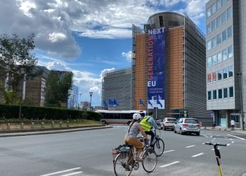 A rider passes with her bike in front of EU Headquarters in Brussels, Belgium