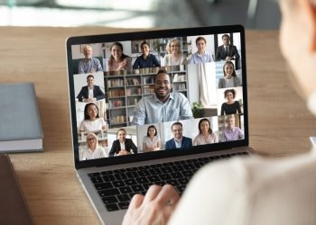 Back view of female employee speak talk on video call with diverse multiracial colleagues on online briefing, woman worker have Webcam group conference with coworkers on modern laptop at home