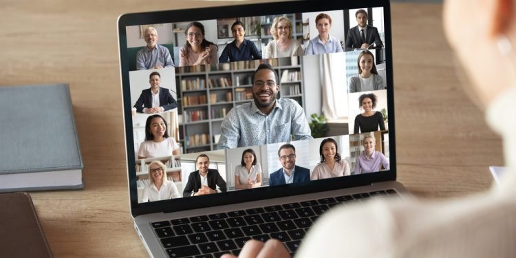 Back view of female employee speak talk on video call with diverse multiracial colleagues on online briefing, woman worker have Webcam group conference with coworkers on modern laptop at home