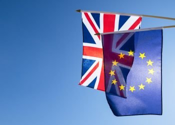 European Union and British Union Jack flag flying in front of bright blue sky