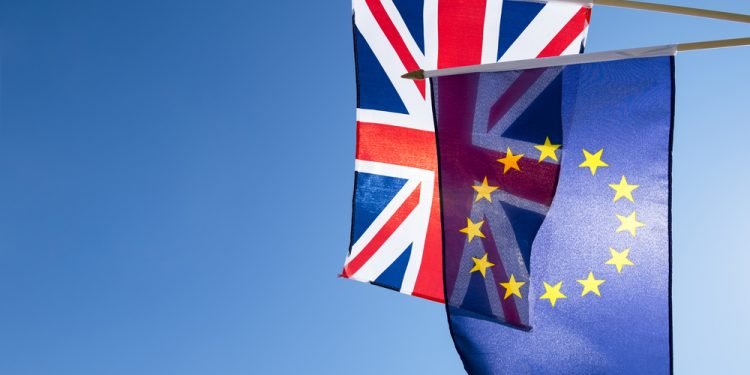 European Union and British Union Jack flag flying in front of bright blue sky