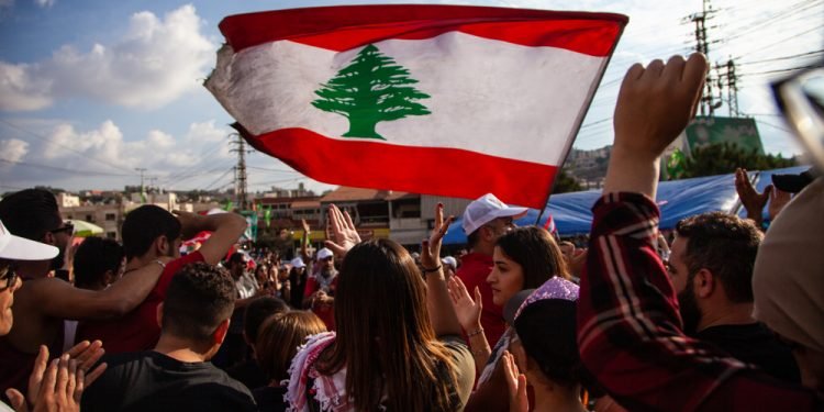 Nabatieh, South Government / Lebanon - 10 20 2019: Lebanese Protesters rising Lebanon Flag in the Sky at the Revolution against the Government