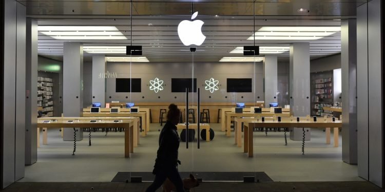 A silhouetted passerby walking a dog passes the exterior of an Apple store as the US technology giant launches new products in Europe and America.