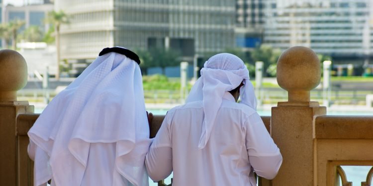 Two anonymous Arab men in traditional white clothing