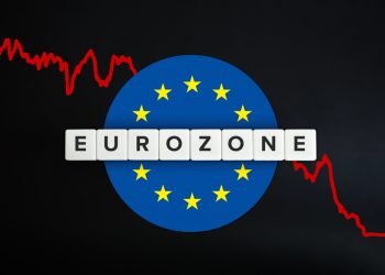 Eurozone or the euro area facing economic recession and decline of economy due to coronavirus or covid-19 crisis. European union (EU) flag, red stock chart and block letters on black background.