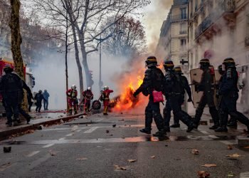 Paris, France: Firefighters extenguishing a car on fire during the Yellow Vests protest against Macron politic.