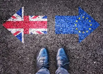 Brexit, flags of the United Kingdom and the European Union on asphalt road with legs