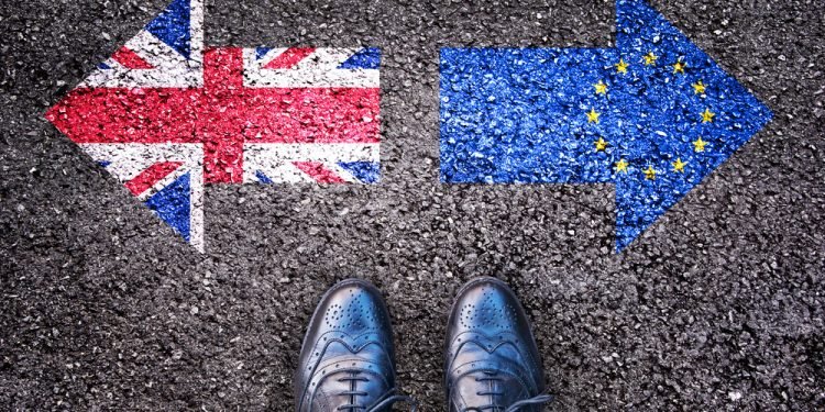 Brexit, flags of the United Kingdom and the European Union on asphalt road with legs