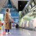 Woman with luggage stands at almost empty check-in counters at the airport terminal due to coronavirus pandemic/Covid-19 outbreak travel restrictions.