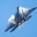 F-22 Raptor in a high-G maneuver, with afterburners on, and condensation clouds and streaks around the plane.