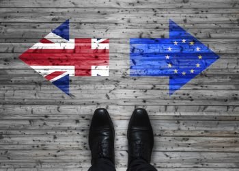 Brexit, flags of the United Kingdom and the European Union on wooden background with legs and shoes