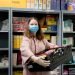 A volunteer at a Trussell Trust food bank wears gloves and face mask PPE in the coronovirus pandemic whilst packing a client parcel