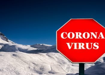 Coronavirus Covid-19 stop sign with ski resort in background.