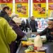 A Supermarket cashier scanning items at the checkout taking items from the conveyor belt that has products on