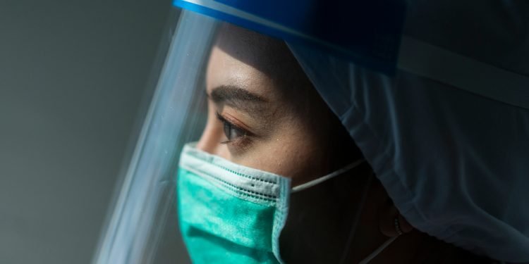 Closeup Asian female Doctor wearing face shield and PPE suit for Coronavirus outbreak or Covid-19