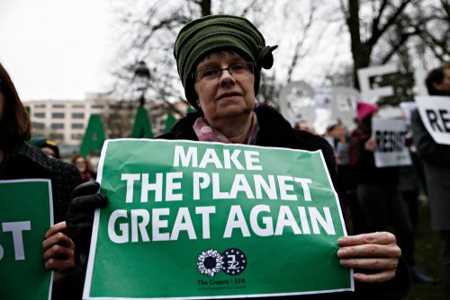 People hold placards and shout slogans during a protest against Trump's environmental policy at conference attended by Trump climate advisor Myron Ebell in Brussels, Belgium on Feb. 2017