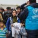 BERKASOVO, SERBIA - OCTOBER 10, 2015: Worker of the UNHCR, the United Nations Agency for refugees, managing a crowd of youg women at the border between Serbia and Croatia