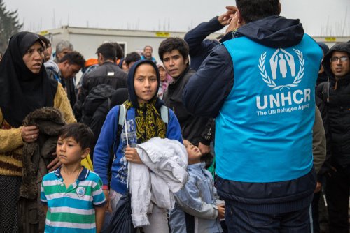 BERKASOVO, SERBIA - OCTOBER 10, 2015: Worker of the UNHCR, the United Nations Agency for refugees, managing a crowd of youg women at the border between Serbia and Croatia