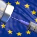 EU Coronavirus vaccine, Europe. Covid-19 vaccination, flu prevention, immunization concept. Vial dose and medical syringe, European Union flag background.