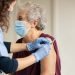 Doctor giving injection to senior woman at hospital.