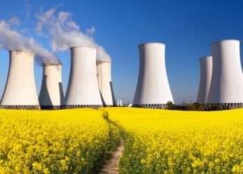 Panoramic view of Nuclear power plant Jaslovske Bohunice with golden flowering field of rapeseed, canola or colza - Slovakia - two possibility for production of electric energy