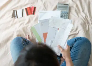 Top view of stressed young asian woman trying to find money to pay credit card debt.