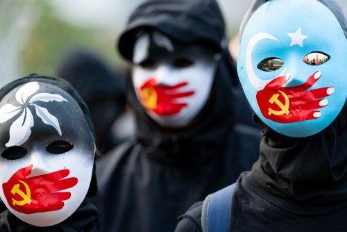 HONG KONG - DECEMBER 22 2019: A group of protestors wear masks symbolizing the Communist Party of China's silencing of Uyghur Muslims and the Hong Kong pro-democracy movement at a rally in Hong Kong.