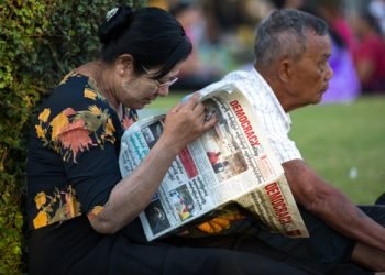 YANGON, MYANMAR - JANUARY 4, 2016: Unidentified woman reading newspaper in the park in Yangon, Myanmar on January 4, 2016