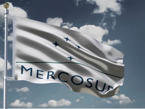 MERCOSUR flag Silk waving flag of South American trade bloc MERCOSUR with emblem four stars green line with a flagpole on a sunny gray blue sky background with white clouds 3D illustration