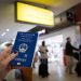 Close up of woman holding a Hong Kong passport over a blurred airport background. Digital composite.