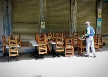 Tables and chairs stacked outside closed cafe-restaurant due the Coronavirus lockdown - Athens, Greece, May 6 2020.