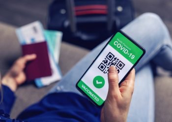 vaccinated person using digital health passport app in mobile phone for travel during covid-19 pandemic