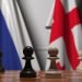 Flags of russia and georgia behind pawns on the chessboard. chess game or political rivalry