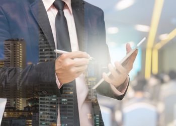 Double exposure of Businessman using the tablet on the Abstract blurred photo of conference hall or seminar room with attendee background