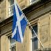 The Scottish Saltire flag on a flagpole outside a sandstone building in Edinburgh, Scotland.