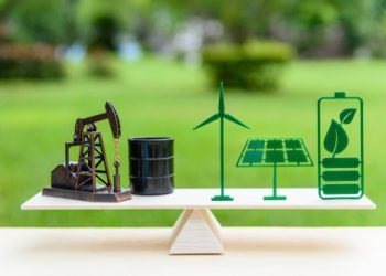 Fossil fuel vs renewable / future clean alternative energy concept : Petroleum pumpjack, crude oil drum barrel, solar panel, green leaf battery, wind turbine on a wood balance scale in equal position.