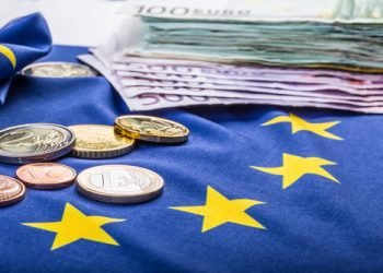Euro,Coins,And,Banknotes,Freely,Laid,On,The,European,Flag.