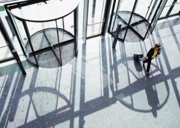 Overhead shot of a businesswoman walking through revolving door with a suitcase in her hand with copy space available.