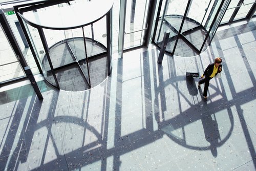 Overhead shot of a businesswoman walking through revolving door with a suitcase in her hand with copy space available.