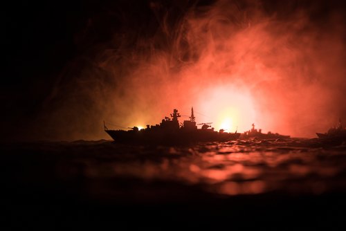 War concept. Night battle scene at sea. Dramatic toned clouds effect. Silhouette of the battle ship in night. Miniature creative table decoration. Selective focus