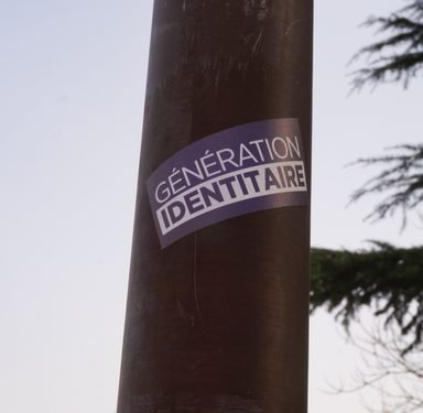 Albi, France - Feb. 2021 - A blue and white sticker from Génération Identitaire, a right-wing youth movement opposing the migratory invasion and the Islamization of Europe, pasted on a lamp post pole