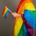 Gay man wearing pink t shirt and a rainbow flag