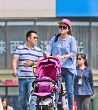 BEIJING-APRIL 28, 2016. Young mother with baby car on pedestrian bridge. China has scrapped its one-child policy. Government allow couples to have two children motivated by demography and economics.