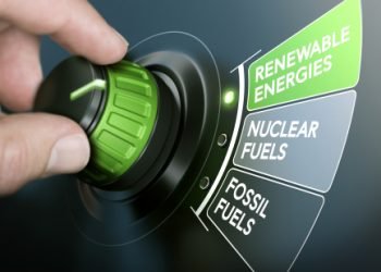 Man turning an energy transition button to switch from fossil fuels to renewable energies. Composite image between a hand photography and a 3D background.