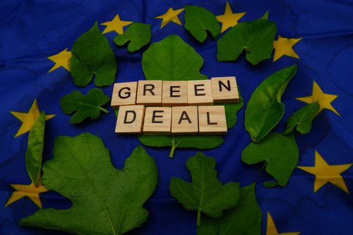 Some leaves,with a wooden inscription,green deal,above a European flag. Concept of fighting climate change on earth