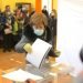 Sofia, Bulgaria - Apr 4 2021: A woman in protective mask and gloves is putting her vote into the voting urn