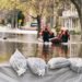 Flood Protection Sandbags with flooded homes in the background (Montage)