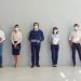 Social Distancing at Work concept. Office workers or job candidates in protective face masks standing in corridor. Applicants waiting for interview keeping safe distance to prevent spread of Covid 19